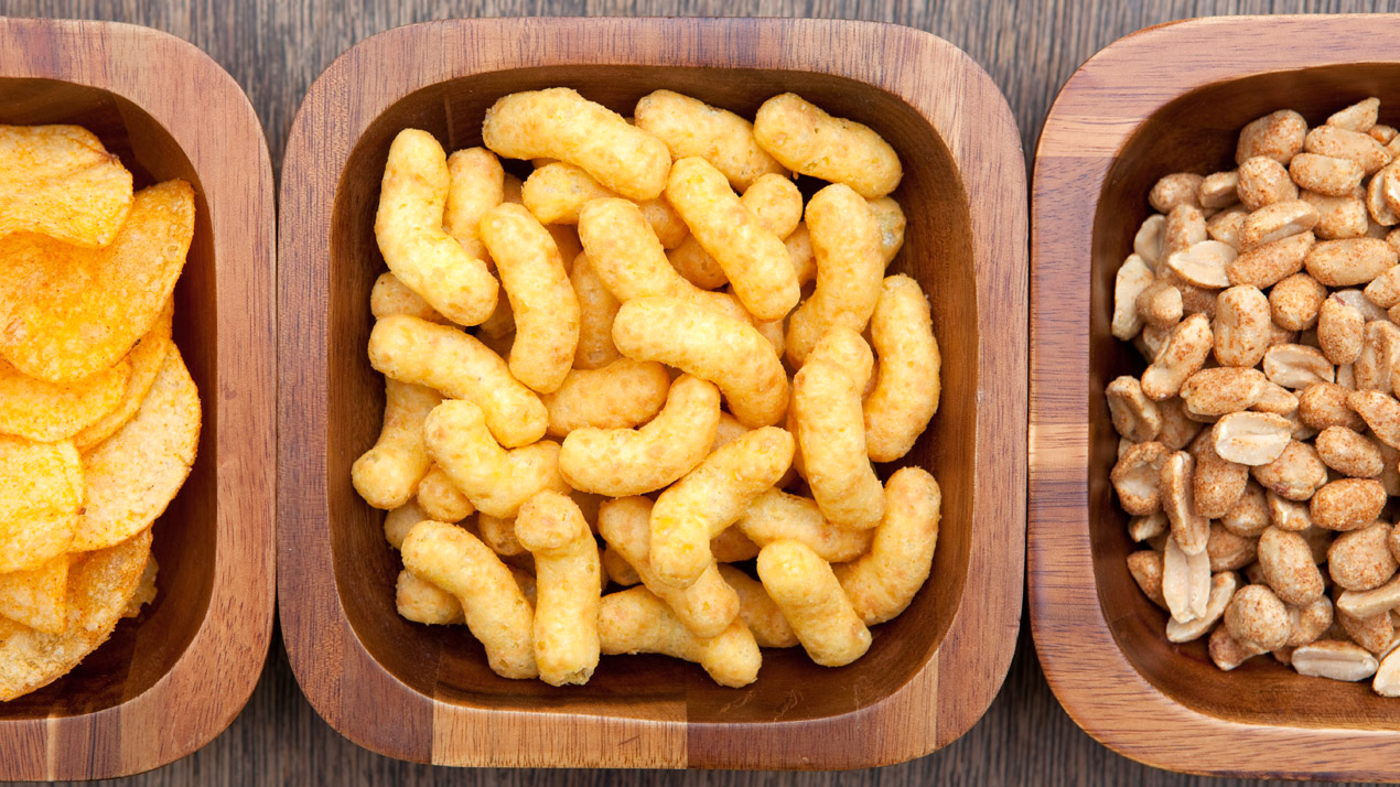 Tre tr&auml;sk&aring;lar med snacks: chips, ostb&aring;gar och torrostade jordn&ouml;tter.