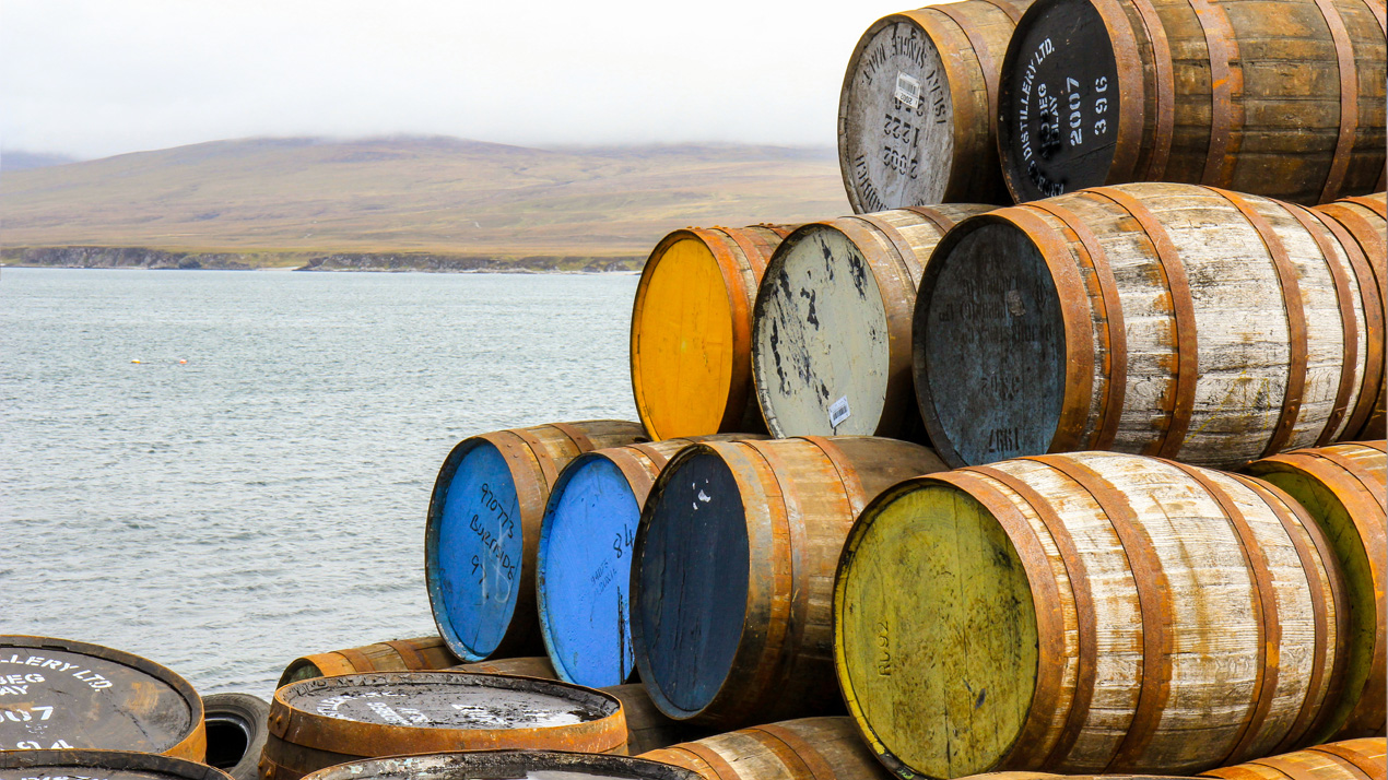 H&ouml;g stapel med ekfat i olika f&auml;rger som ligger staplade p&aring; kajen p&aring; &ouml;n Islay.