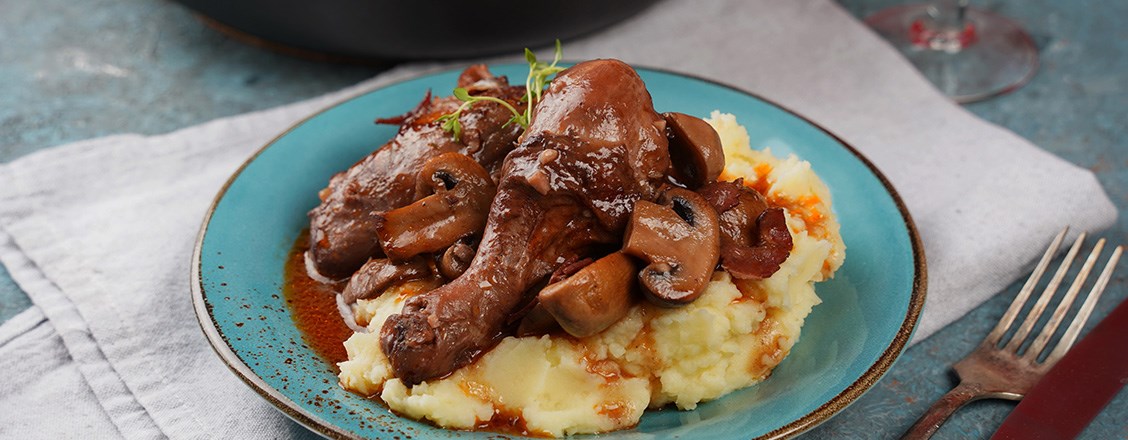 Maträtten coq au vin på turkosblå tallrik