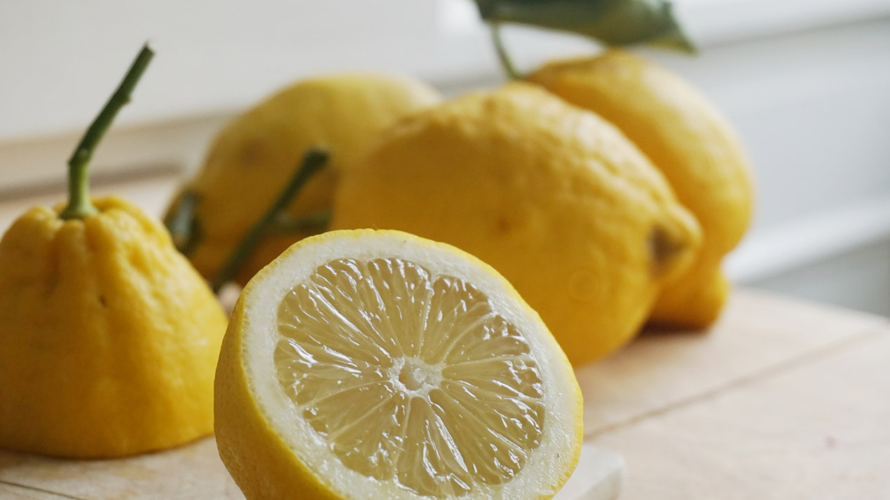 Hela och delade citroner på skärbräda.