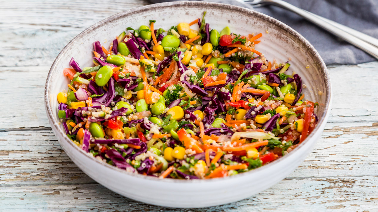 Färgrik bulgursallad i rustk skål på träbord.